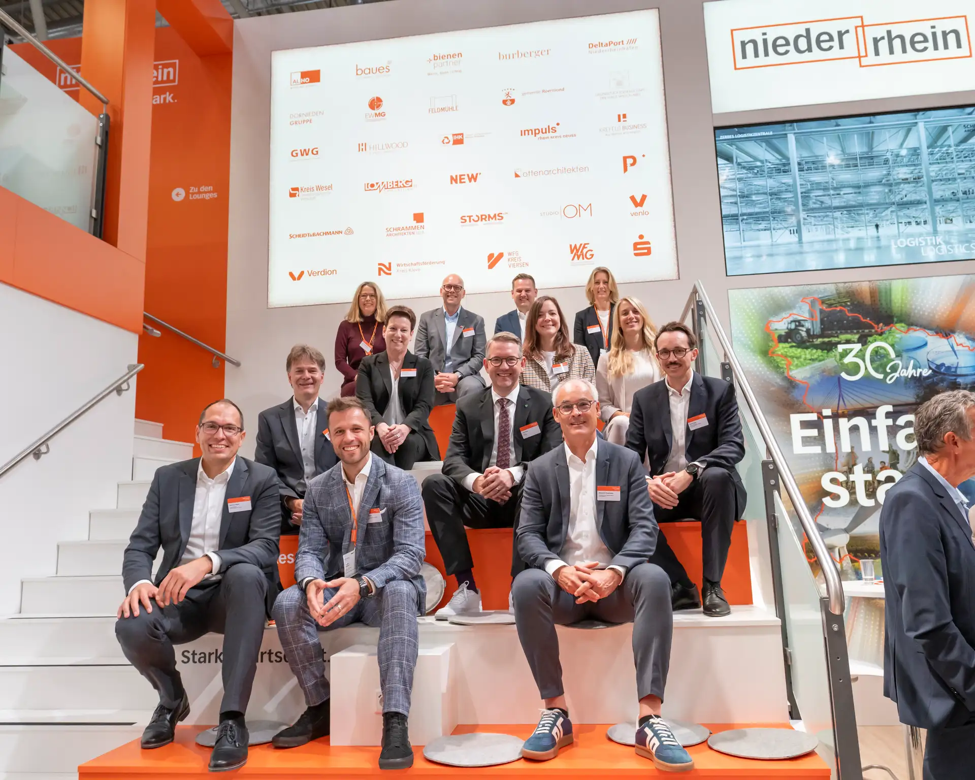 Mehrere Personen stehen gemeinsam für ein Gruppenfoto, vorn in einer Reihe (v.l.n.r. nach Bildunterschrift).