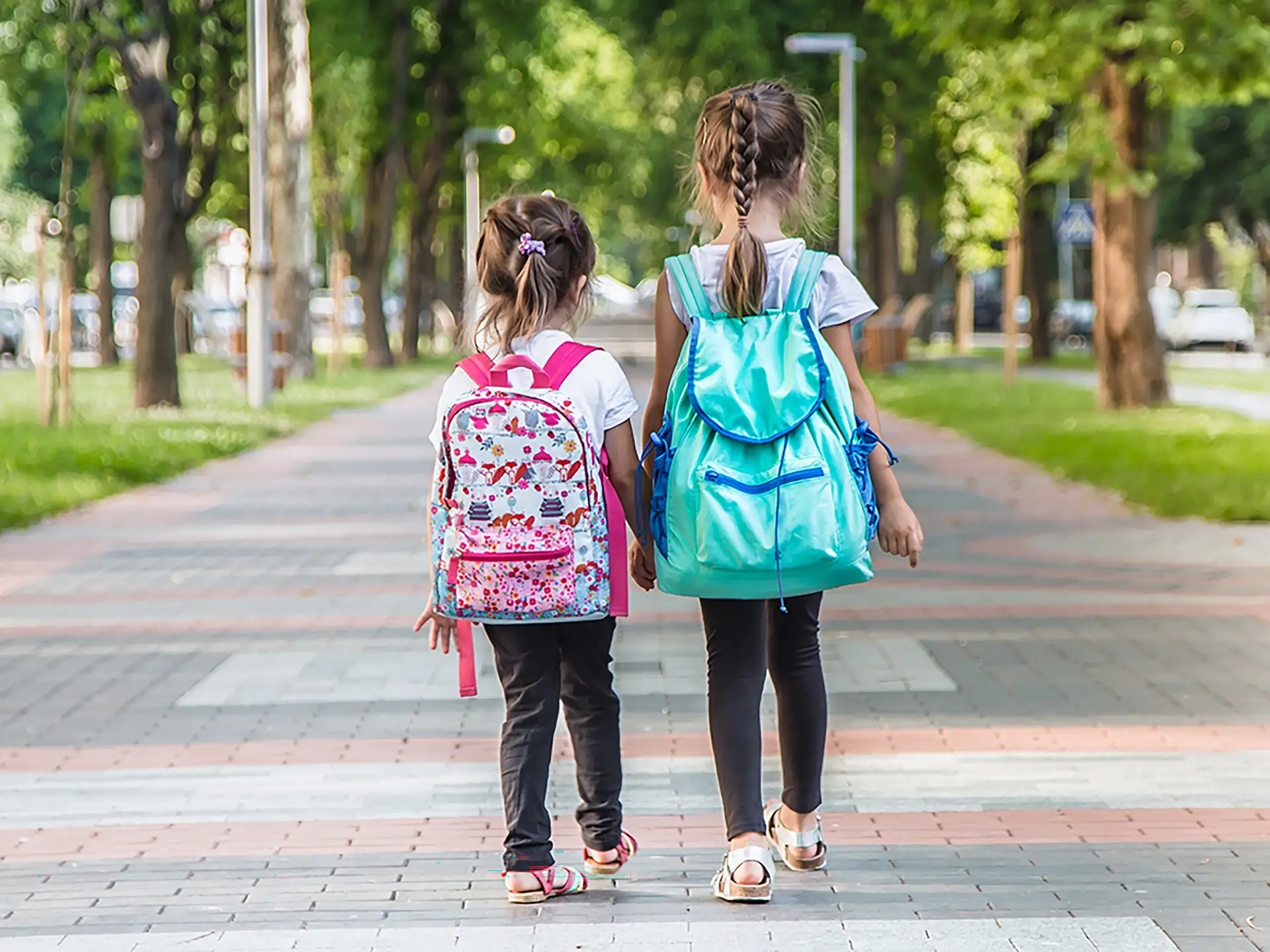 Back to school education concept with girl kids, elementary students, carrying backpacks going to class on school first day holding hand in hand together walking up building stair happily